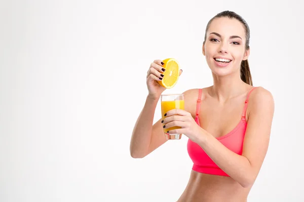 Fitness girl pressing orange juice into a glass — ストック写真