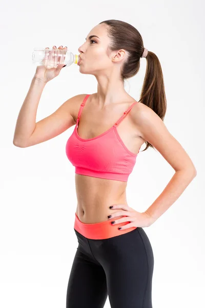 Profile of attractive young sportswoman drinking water — ストック写真