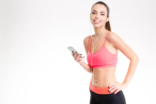 Fitness girl listening to music from cell phone using earphones — Stockfoto