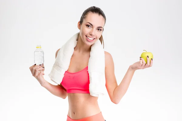 Fitness girl with towel holding bottle of water and apple — Stock Photo, Image