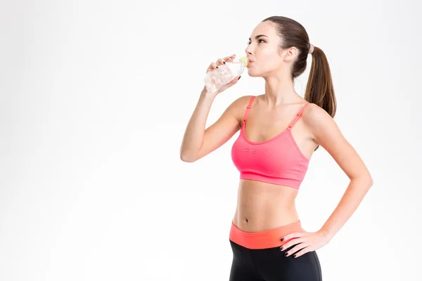 Beautiful young fitness woman drinking water from plastic bottle — Stock Photo, Image