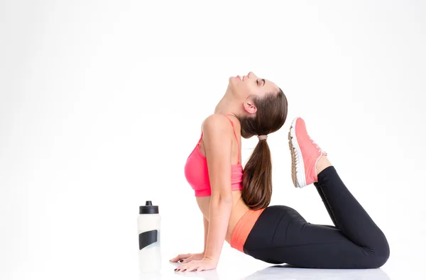 Smiling natural sportswoman with bottle of water doing stretching exercises — 图库照片