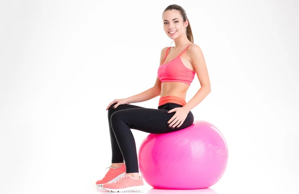 Fröhliche attraktive junge Sportlerin sitzt auf rosa Fitball — Stockfoto