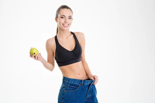 Sportvrouw in grote jeans werd mager en houden een appel — Stockfoto