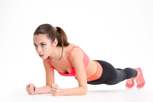 Concentrated beautiful fitness girl in sportwear exercising doing plank — Stock Photo, Image