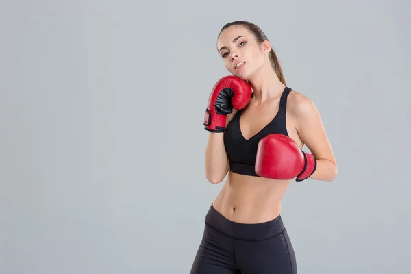 Уверенная в себе довольно фитнес девушка позирует в красных боксерских перчатках — стоковое фото