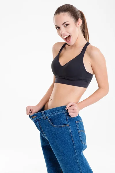 Amazed happy fitness woman became skinny and wearing old jeans — Stock Photo, Image