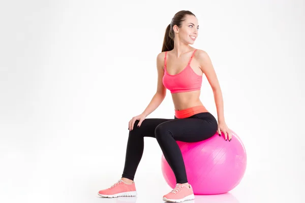 Cheerful pretty young fitness woman sitting on pink fitball — Stock Photo, Image