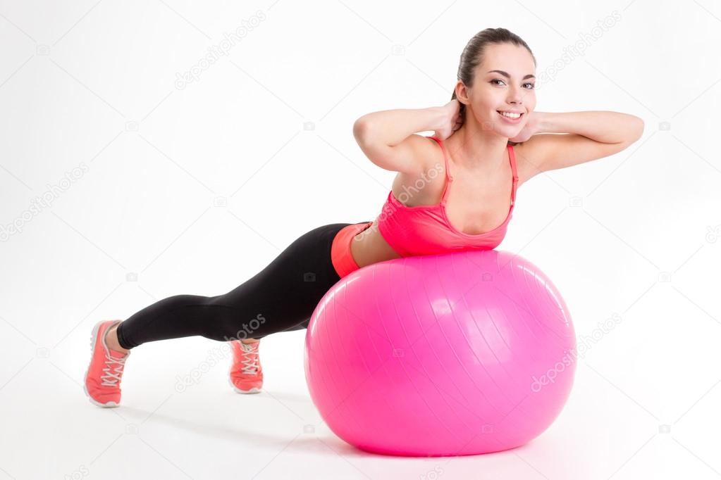 Pretty smiling young sportswoman exercising with fitball 