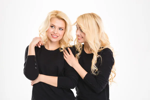 Atraente alegre jovem loira irmãs gêmeos falando e olhando para longe — Fotografia de Stock