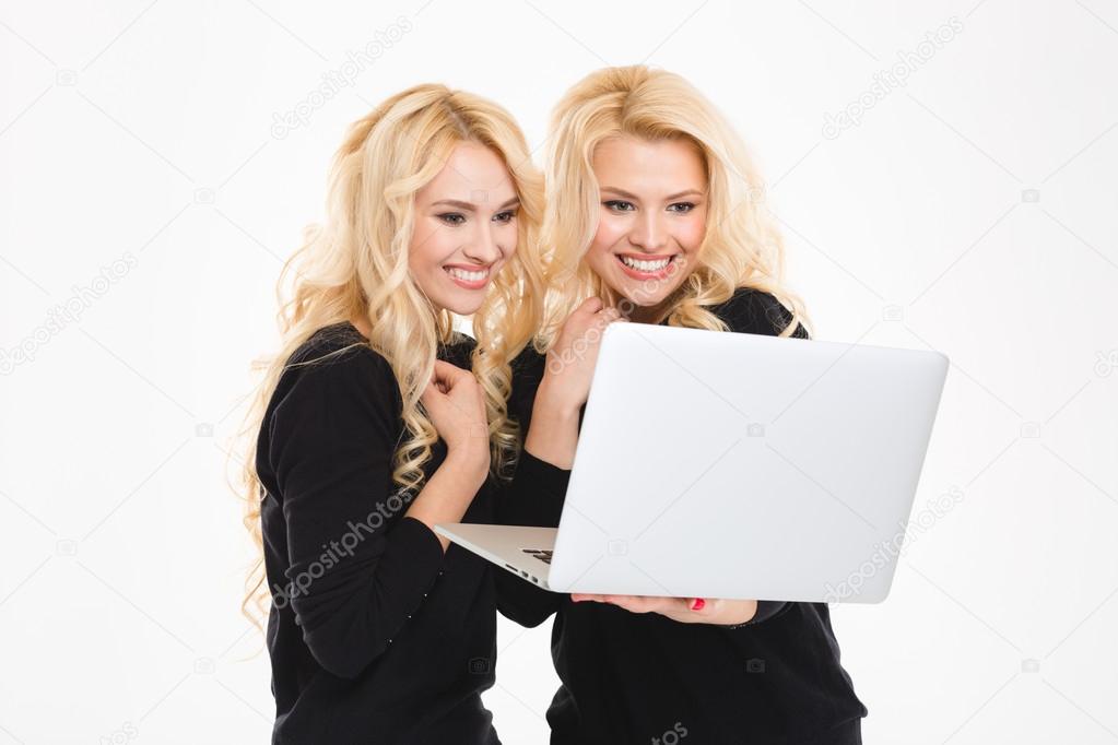 Pretty sisters twins using laptop computer