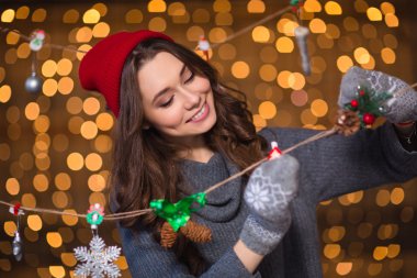 Smiling girl making handmade christmas decoration over holidays lights background