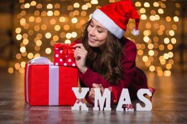 Attractive woman lying near letters spelling word Xmas and presents