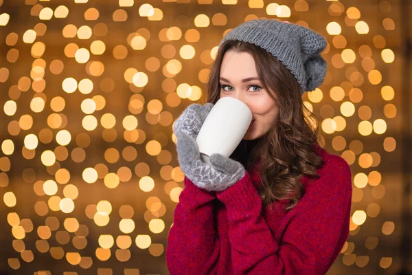 Beautiful woman in grey hat and mittens drinking hot chocolate — ストック写真