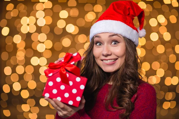 Divertente positivo giovane donna in possesso di un regalo su sfondo brillante — Foto Stock