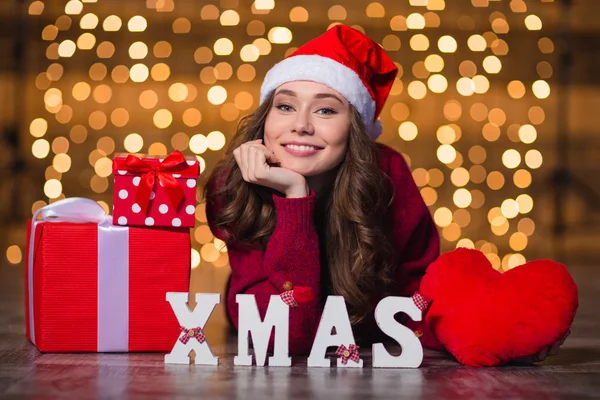 Fröhlich schönes Mädchen liegt in der Nähe von Buchstaben buchstabieren Wort Weihnachten — Stockfoto