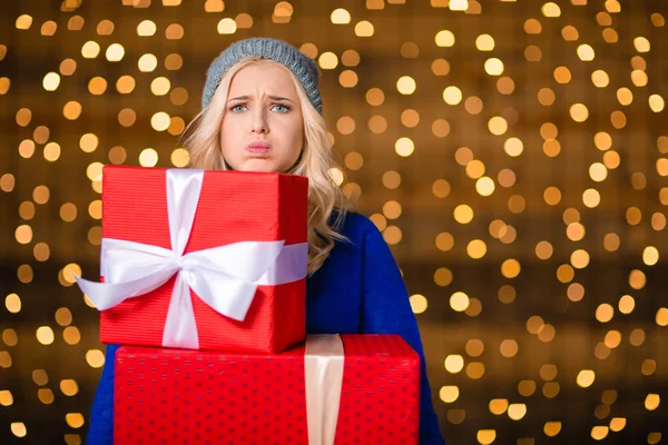 Woman holding gift boxes over holidays lights background — Φωτογραφία Αρχείου