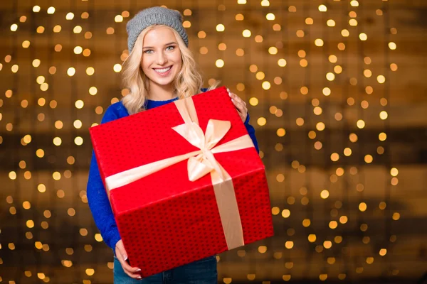 Woman holding gift box over holidays lights background — Stock Fotó
