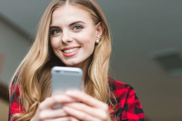 Radostné okouzlující blondýna mladá žena pomocí smartphone — Stock fotografie