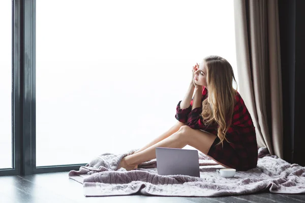 Beautiful pensive woman sitting with laptop and cup of coffee — Stock Photo, Image