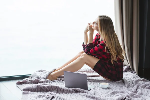 Atraktivní promyšlené samice sedí na podlaze a při pohledu přes okno — Stock fotografie