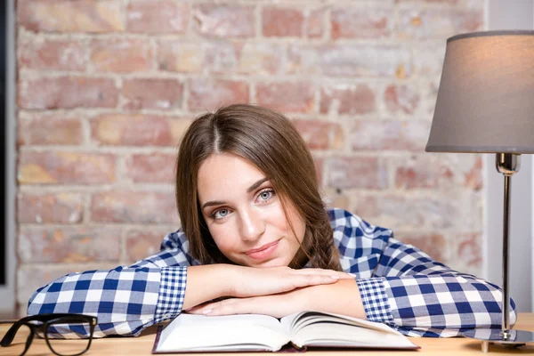 Donna felice seduta a tavola con libro — Foto Stock