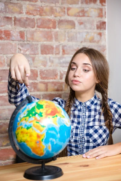 Vrouwelijke student zitten aan de tafel met globe — Stockfoto