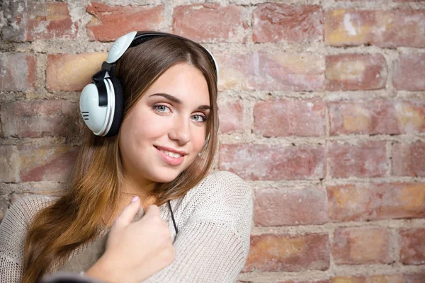 Leende kvinna lyssnar musik i hörlurar — Stockfoto