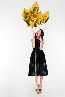 Full length of beautiful curious girl pointing on golden balloons