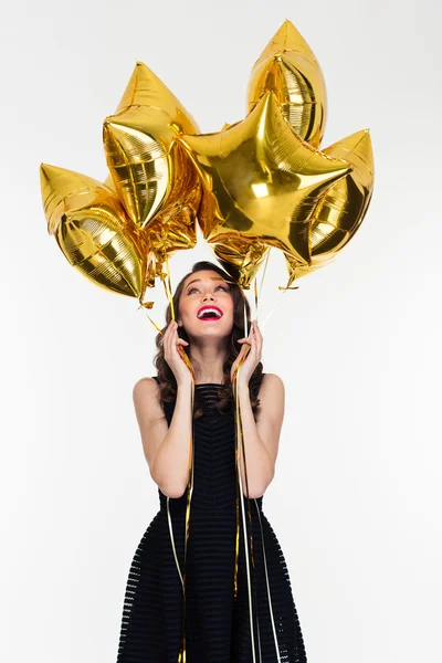 Joyful beautiful young female looking up on star shaped balloons — Stockfoto