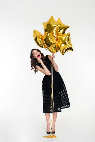 Amusing cheerful lovely curly girl  holding golden balloons — Stockfoto