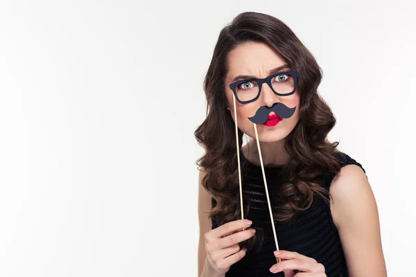 Comical curly young female playing with glasses and moustache booth — Stockfoto