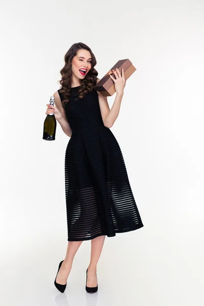 Atractiva mujer guiño celebración botella de champán y regalo — Foto de Stock