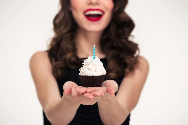 Cheerful beautiful curly young woman giving birthday cupcake with candle — Φωτογραφία Αρχείου