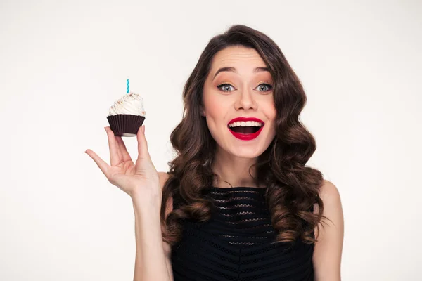 Atractiva excitada joven sonriente sosteniendo cupcake de cumpleaños con vela — Foto de Stock