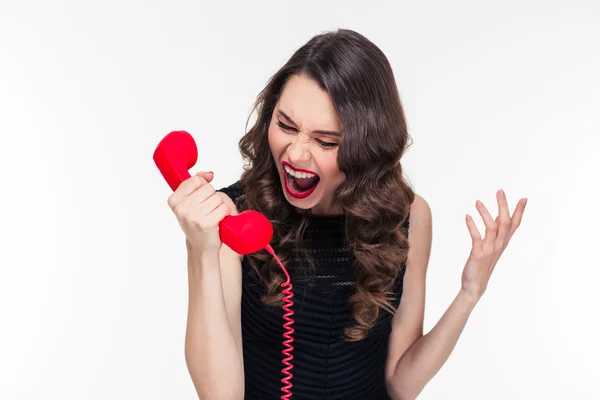 Crazy raged retro styled female shouting in red telephone receiver — 图库照片