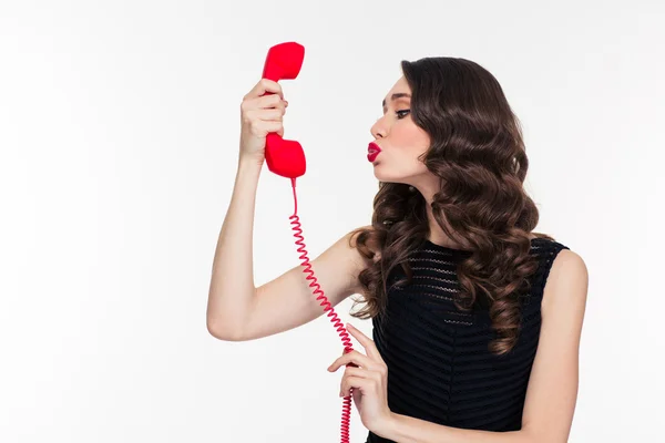 Cute woman in retro style sending kiss into telephone receiver — Stock Photo, Image