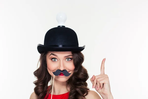 Girl in hat with light bulb using fake moustache props — Stockfoto