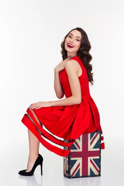 Charming happy woman posing on vintage suitcase with british flag — Stock Photo, Image