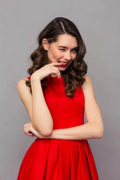 Woman in red dress winking at camera — Stockfoto