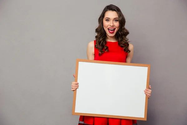 Vrolijke vrouw bedrijf leeg bord — Stockfoto