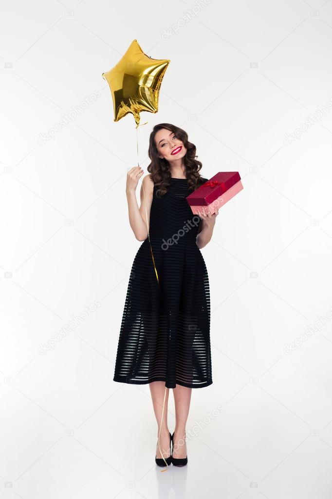 Smiling woman holding golden star shaped balloon and present box