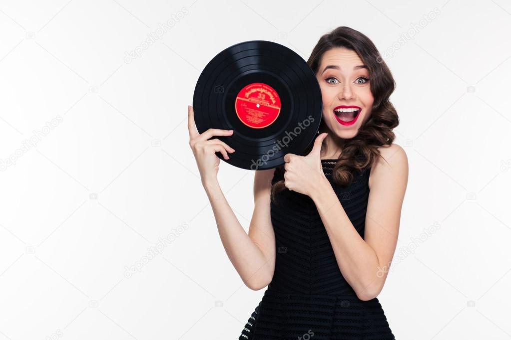 Beautiful positive woman holding vinyl record and showing thumbs up 