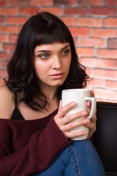 Atraente pensivo jovem mulher sentado e bebendo chá — Fotografia de Stock