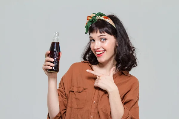 Smiling beautiful woman pointing on bottle of sweet carbonated beverage — Stockfoto