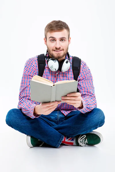 Attraktiver bärtiger Student mit Kopfhörern, der sitzt und Buch liest — Stockfoto