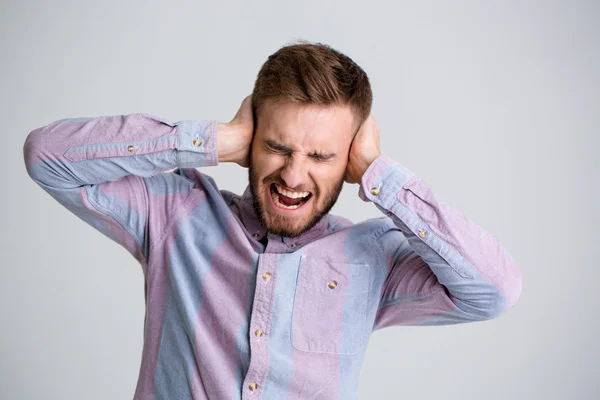 Yakışıklı kızgın adam kapalı kulakları eller ve bağırarak sakallı — Stok fotoğraf
