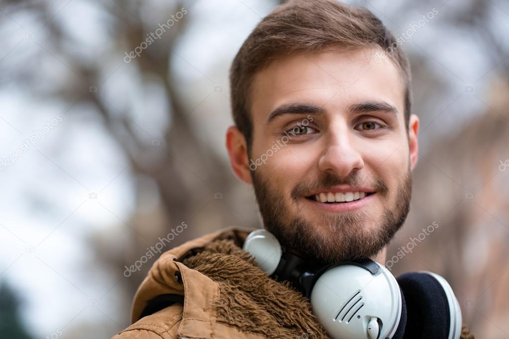 Close up of cheerul attractive bearded young male with headphones 