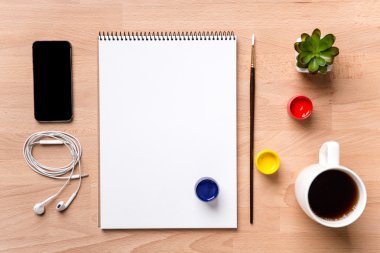 Not Defteri, boya fırçası, boyalar, smartphone, kulaklık ve kahve 