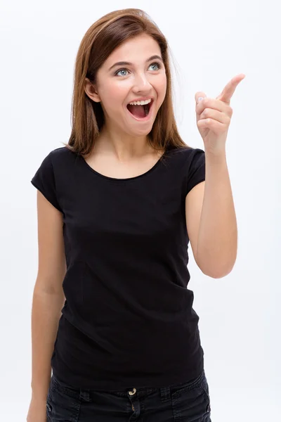Förvånad glad ung kvinna som pekar bort — Stockfoto